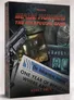 A boxed set titled "Blade Runner: The Roleplaying Game - Asset Pack" features a striking design with a prominent black handgun and various images, including a crime scene and a digital display of replicant faces. The front cover includes the title in bold red letters, along with the text "ASSET PACK" at the bottom. A newspaper headline reads "ONE YEAR OF REPLICANTS WHERE ARE THEY NOW," adding to the thematic elements of the Blade Runner universe.