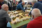 Two men playing a miniature wargame on a detailed battlefield model with tiny figures and terrain.