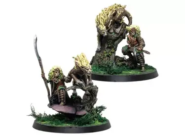 A pair of intricately detailed miniatures from Corvus Belli, featuring a character with long, wild hair wielding a spear, accompanied by a large, stylized creature resembling a lion with a mane of flames. The figures are set on a base adorned with lush green grass and a gnarled tree, enhancing the naturalistic theme. The character appears to be in a dynamic pose, suggesting action or readiness, while the creature stands alert beside them.