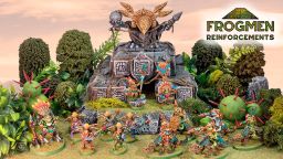 A vibrant scene showcases a variety of colorful Space Frogmen miniatures, including a frogman chieftain and cavalry, positioned around a rocky outcrop adorned with ancient symbols and a large decorative skull. Lush greenery and spiky plants surround the figures, enhancing the fantastical atmosphere. The text "FROGMEN REINFORCEMENTS" is prominently displayed in the corner, indicating the theme of the Kickstarter campaign.