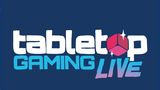 The logo for "Tabletop Gaming Live" features bold, playful typography on a dark blue background. The word "tabletop" is in white, while "GAMING" is in a vibrant blue, and "LIVE" is in a gradient of pink to purple, with a stylized red gaming die incorporated into the design. The overall look is dynamic and inviting, reflecting the excitement of the event.