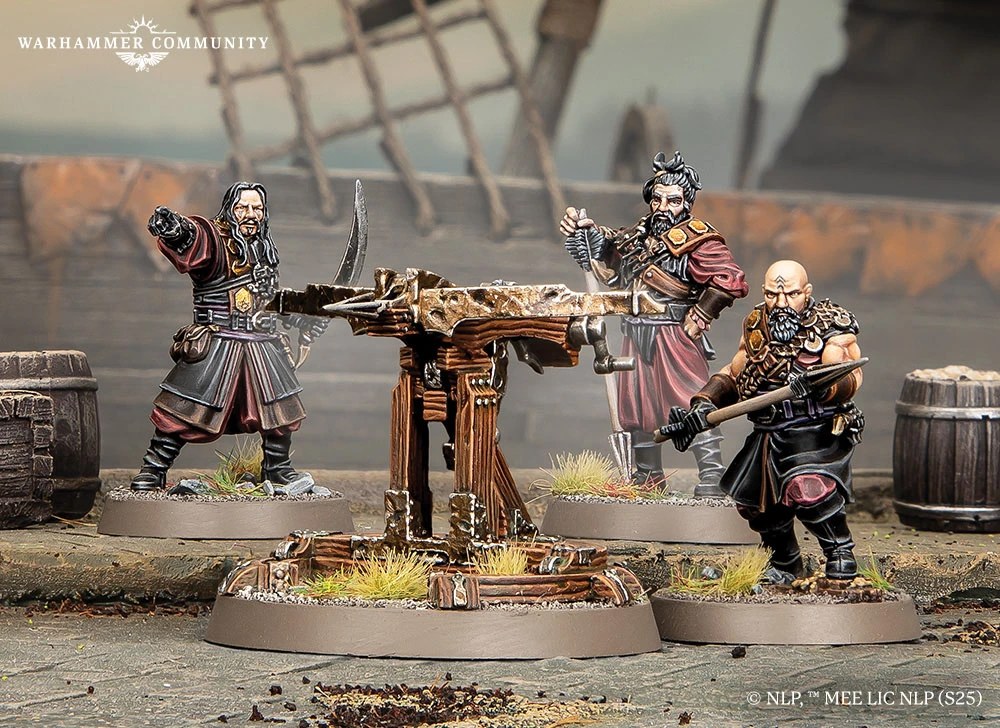 A detailed scene features a wooden Umbar ballista at the center, supported by a sturdy base and surrounded by tufts of grass. Flanking the ballista are three miniature corsairs, each dressed in dark, rugged attire, with one holding a sword and another gesturing with a hand raised. The background includes hints of a weathered environment, with barrels and a blurred structure, enhancing the atmosphere of a battle-ready setting.