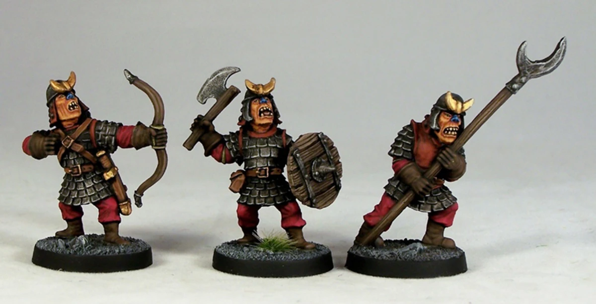 Three fantasy miniatures are displayed, each depicting a character in armor with distinct features. The first figure on the left holds a bow, while the middle figure wields an axe and a shield, showcasing a fierce expression. The third figure on the right is armed with a spear, all standing on textured bases with a hint of grass. Each miniature is painted with vibrant colors, emphasizing their detailed armor and facial expressions.