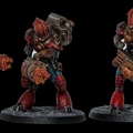 Three intricately designed miniatures stand against a black background, showcasing a futuristic aesthetic. Each figure features a robust build with prominent red and blue armor, detailed mechanical components, and unique weaponry, including a large, cylindrical device and a smaller, handheld weapon. The bases are textured to resemble rocky terrain, enhancing the overall sci-fi theme of the miniatures.