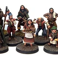 A collection of detailed miniatures representing various fantasy tavern patrons and villagers, arranged in two rows on textured bases. The figures include a mix of characters such as a hooded figure, a woman holding a tray of baked goods, and several others in period-appropriate attire, showcasing a variety of poses and expressions. The overall scene captures the lively atmosphere of a fantasy tavern setting, ideal for tabletop RPGs.