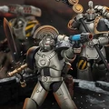 A squad of Iron Warriors action figures is prominently displayed, showcasing their detailed designs and articulation. The foreground features a Sergeant wielding a power sword and a plasma pistol, while a command squad member stands behind, holding a staff. The figures are set against a dramatic backdrop, enhancing their imposing presence with hints of smoke and debris.
