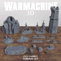 A collection of 3D printed terrain pieces from the Warmachine "Old Umbrey Terrain Set" is displayed on a wooden surface. The set includes a large, intricately designed building with pointed towers, a tall stone tower, and several smaller terrain elements like rocky outcrops, trees, and fences. Various bases and scatter terrain pieces are arranged around the central structures, showcasing a mix of natural and architectural features, all in a gray color. A pair of dice is also visible in the foreground.