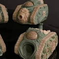 A collection of four unique, grotesque tank models designed for a Chaos army, showcasing a variety of disturbing features such as orifices, boils, and eyeballs. The tanks are sculpted in a mix of green and beige materials, with intricate details on their surfaces, including textured tracks and organic shapes. Each model has a distinct design, emphasizing a visceral aesthetic that aligns with the themes of Chaos in the 41st Millennium.