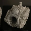 A grotesque tank model designed for a Chaos army, featuring a textured surface adorned with various orifices, boils, and an eye-like detail on the front. The tank has a large, gaping mouth-like opening, emphasizing its disturbing aesthetic. The model is presented in a gray, unpainted finish, showcasing intricate sculpting details that highlight its bizarre and unsettling design.
