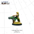 A miniature figure of a Commando Chain Gunner stands confidently, wielding a large chain gun. The figure is dressed in green tactical gear, with a headband and long blonde hair, and is positioned on a base with tufts of grass. The background is a simple grid pattern, emphasizing the figure's details and colors.