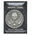 A collectible coin featuring a prominent skull surrounded by laurel leaves, set against a dark, starry background. The coin is labeled "IMPERIAL LAUREL" at the top and "COLLECTABLE COIN" at the bottom, with additional text in multiple languages. The design reflects the Warhammer 40,000 theme, emphasizing its collectible nature.