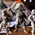 A collection of miniature pirate figures is displayed on a wooden surface, showcasing a variety of characters. In the foreground, a prominent pirate captain with a skull-adorned hat and a long beard holds a sword aloft, exuding a commanding presence. Beside him, a female pirate brandishes a cutlass, while other figures, including an undead pirate, are partially visible in the background, all rendered in a light-colored material that highlights their intricate details.