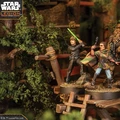 A group of four detailed miniatures from the Star Wars franchise stands on a wooden platform surrounded by lush greenery. The characters include a young man wielding a green lightsaber, a woman holding a blaster, and a figure resembling Chewbacca, alongside another character in a brown coat. The scene is set in a vibrant, natural environment, enhancing the adventurous theme of the miniatures.