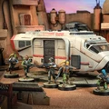A detailed scene features a Speeder Truck, a large, futuristic vehicle with a sleek design and a prominent red stripe, set against a backdrop of a desert-like environment. Surrounding the truck are five miniature figures, each armed and dressed in varied outfits, including a mix of green and brown tones, suggesting a rugged, adventurous theme. The ground is textured with sandy terrain, and additional elements like crates and structures can be seen in the background, enhancing the immersive atmosphere.