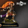 Kishtaar the Conqueror is depicted as a fierce warrior in ornate brass-faced armor adorned with intricate details and horned accents. She has long, flowing orange hair and stands confidently on a textured base with patches of grass. The figure is posed dynamically, holding a weapon in one hand, emphasizing her role as a powerful leader in the Warmachine universe. The name "KISHTAAR THE CONQUEROR" is displayed prominently at the bottom of the image.