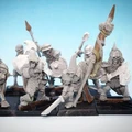 A collection of 28mm scale skeleton warriors from Diehard Miniatures, featuring several figures in various poses. The miniatures are equipped with weapons such as spears and swords, and are adorned with armor and helmets reminiscent of classic Oldhammer designs. The background is a soft blue gradient, highlighting the details of the skeletal figures, which are mounted on black bases.