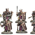 A group of five Zharrdron warriors stands in a dynamic formation, each clad in dark, ornate armor with intricate detailing. They wield a mix of weapons, including swords and shields, with some featuring glowing green accents. The warriors are set against a simple base with tufts of grass, emphasizing their imposing presence and the dark, industrial aesthetic of their design.