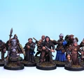 A diverse group of painted miniatures stands against a light blue background, showcasing various adventurers and characters. The figures include a mix of warriors, spellcasters, and rogues, each detailed with unique clothing, weapons, and expressions. They are mounted on circular bases with tufts of grass, highlighting their fantasy theme and adding to the overall aesthetic of the collection.