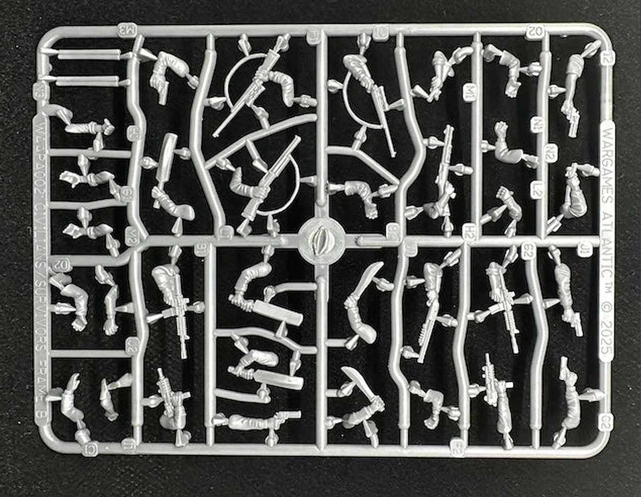 A plastic sprue featuring various components for miniature figures, including torsos, limbs, and heads, designed for 28mm scale modern civilians and post-apocalyptic survivors. The sprue showcases a variety of poses and accessories, including weapons, allowing for customization of the miniatures. The pieces are molded in a light gray plastic and are arranged in a grid pattern on a black background.