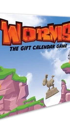 A colorful box for "Worms: The Gift Calendar Game" features a vibrant illustration of cartoonish landscapes with green hills and rocky cliffs. Prominent characters include a pink worm wearing a crown and a knight, both positioned on the cliffs, while a hot air balloon floats in the sky. The title is boldly displayed at the top, emphasizing the festive theme of the advent calendar.