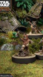 A group of four Ewok miniatures from the Star Wars: Legion game is displayed on circular bases, set against a lush, green forest backdrop. Each Ewok is uniquely posed: one holds a spear, another brandishes a slingshot, while the others are equipped with various weapons and accessories. The terrain features rocks, foliage, and remnants of a crashed vehicle, enhancing the scene's immersive quality.