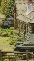 A detailed tabletop scene features several miniature tanks amidst a rural setting, including a wooden cabin and lush greenery. In the foreground, a tank with the number "600" is positioned near a wooden fence, while another tank is seen further back with a crew member visible. The background includes trees and additional structures, creating a vibrant battlefield atmosphere.