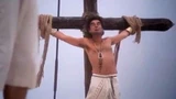 Movie still of crucifixion theme from 'The Life of Brian' where a man is bound to a cross.