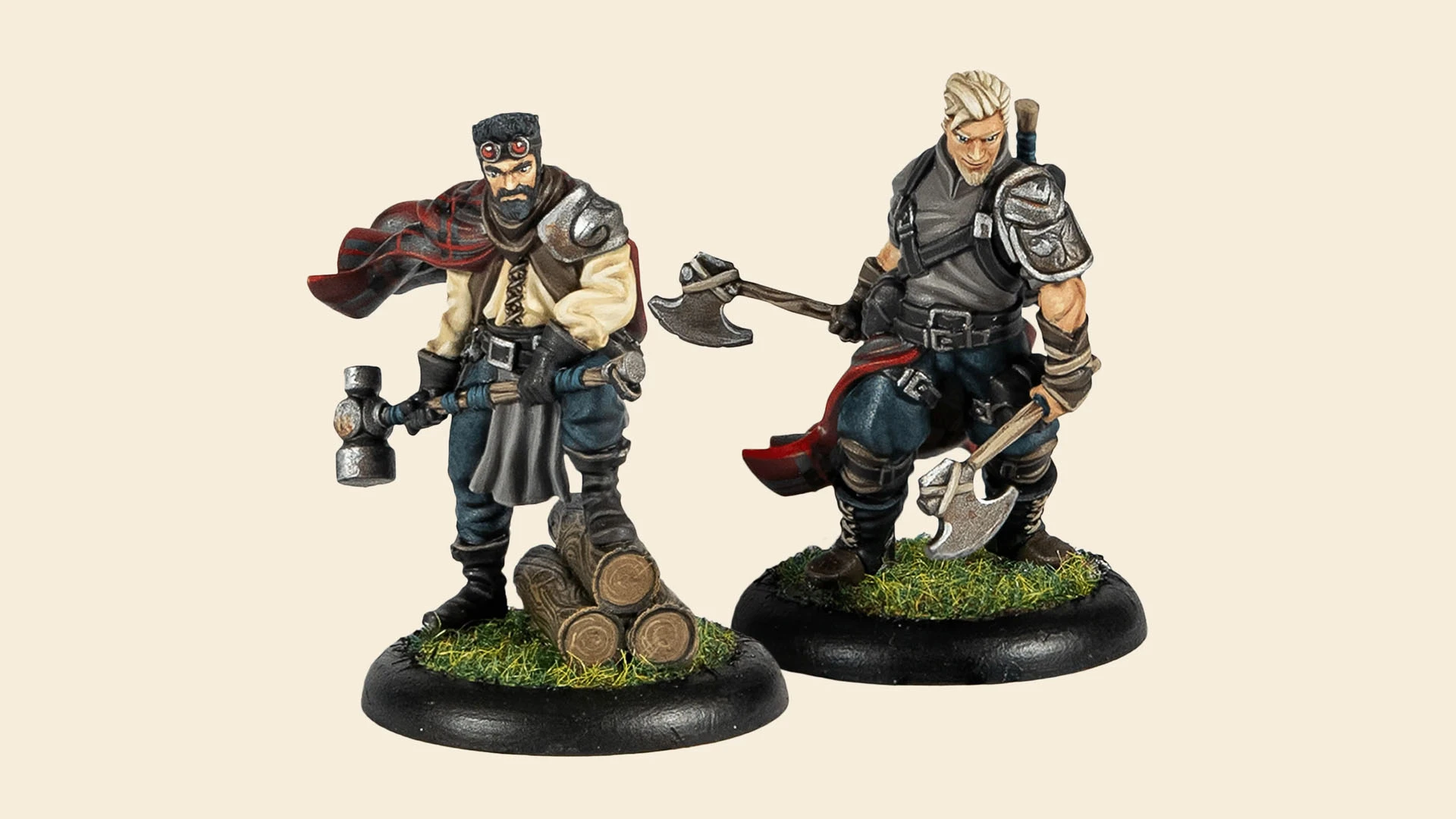 Two detailed miniatures from the new Lumberjacks team for Guild Ball are displayed. On the left, a character with a beard and a red scarf stands confidently next to a small stack of logs, holding a large axe. On the right, a muscular figure with blonde hair and a serious expression wields a similar axe, dressed in dark clothing with armor accents. Both figures are mounted on circular bases with green grass detailing.