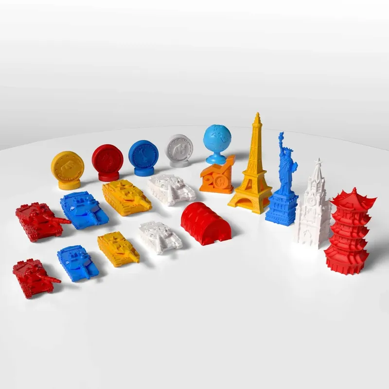 Colorful 3D-printed landmarks, tanks, coins, and barrels on a white surface.