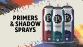 A spray can labeled "P3 SHADOW SPRAYS" in bold black text is prominently featured on a light background, with the specific shade "SANGUINE SHADOW" indicated. Surrounding the can are splashes of vibrant colors, including blue, red, and white, creating an artistic backdrop. The text "PRIMERS & SHADOW SPRAYS" is displayed above the can, emphasizing the product's focus on painting supplies for tabletop gaming.