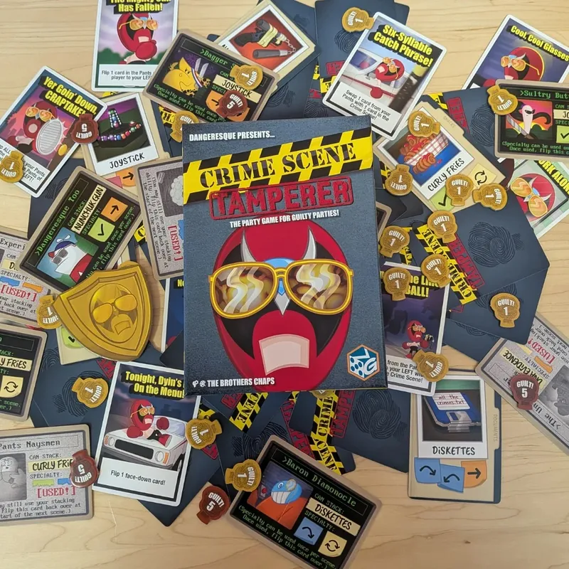 Crime Scene Tamperer game box surrounded by cards and tokens on a wooden table.