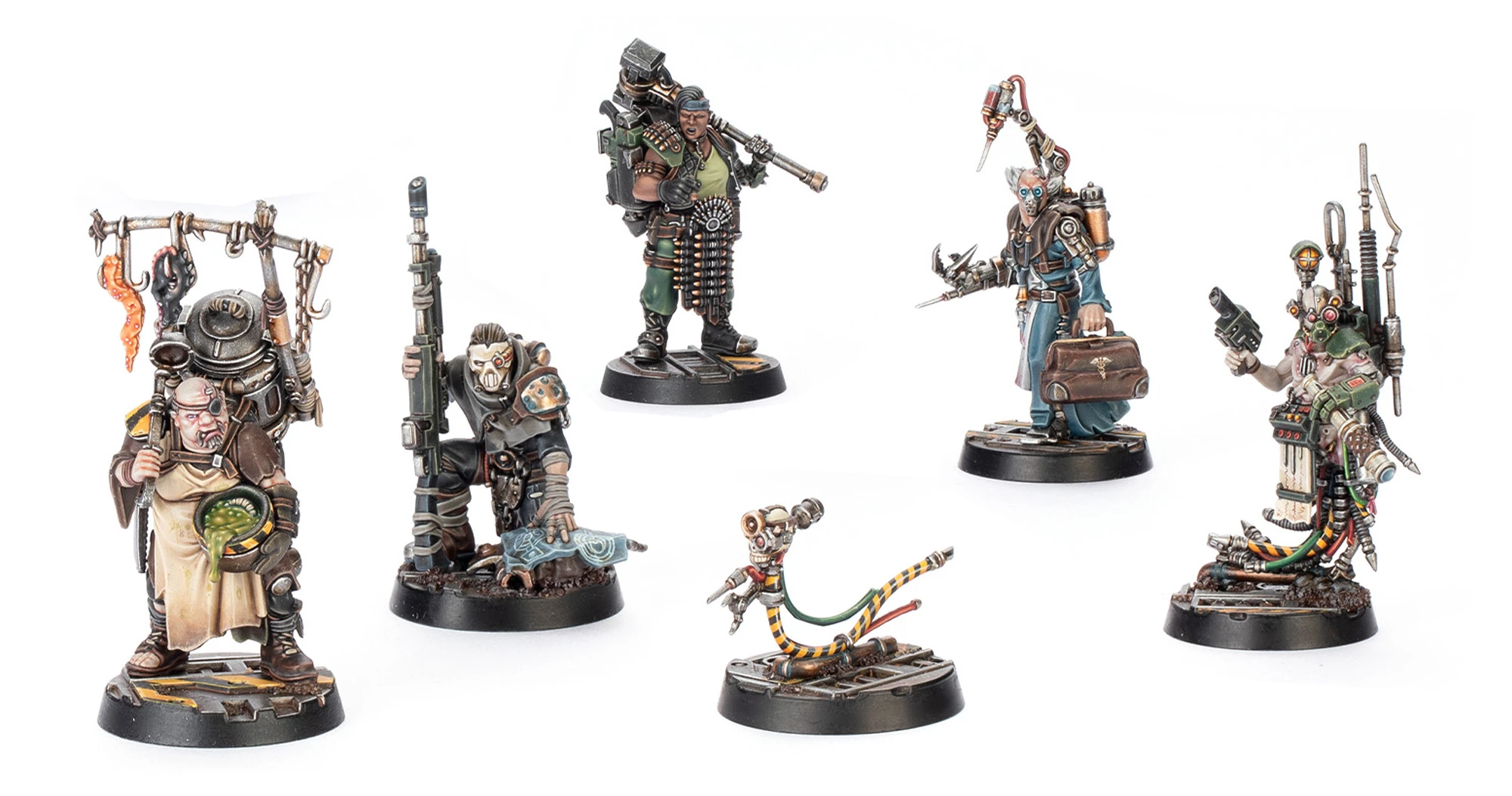 A group of five miniatures from the Underhive Hangers-on set is displayed, showcasing a variety of characters. On the left, a figure holds a rifle and stands on a rocky base, while another character, muscular and equipped with a large weapon, stands confidently in the center. To the right, a character with a mechanical arm and a tool in hand appears focused, alongside a smaller figure resembling a robotic creature with a colorful, striped tail. The miniatures feature intricate details and a gritty, industrial aesthetic typical of the Necromunda setting.