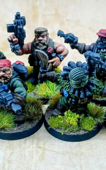 A group of eight intricately detailed miniatures representing space dwarves in a jungle setting, each standing on circular bases adorned with tufts of grass. The figures are dressed in military-style attire, featuring green clothing and red caps, with various weapons including guns and a curved blade. Their expressions are fierce and determined, showcasing a blend of ruggedness and character typical of old-school metal miniatures.