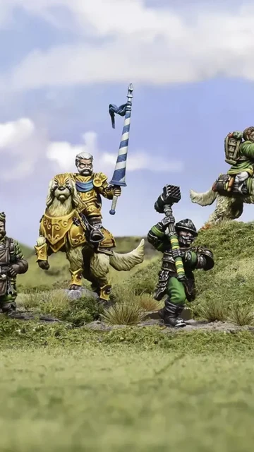A group of halfling miniatures stands on a grassy terrain, showcasing their unique characteristics. In the center, a halfling in ornate armor rides a large, lion-like creature, holding a blue and white banner. To the left, another halfling wields a spear, while a third, dressed in green, brandishes a hammer. A fourth halfling rides a smaller, dog-like creature, completing the ensemble of pint-sized warriors. The background features a soft blue sky with scattered clouds, enhancing the whimsical atmosphere.