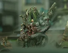 Green-skinned monster with long hair, horns, and a staff, holding a severed head.