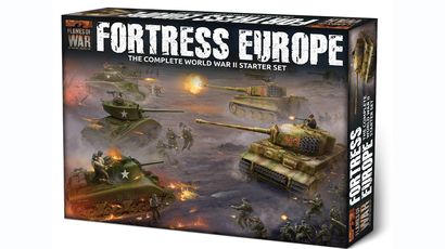 A box for the "Fortress Europe" starter set for the Flames Of War wargame prominently displays the title in bold, distressed lettering. The artwork features a dynamic battlefield scene with American and German forces, including tanks and soldiers engaged in combat. The background showcases a smoky, war-torn landscape, enhancing the theme of World War II wargaming.