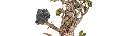 A towering model of Beechbone, an ent from the Middle-earth Strategy Battle game, stands prominently with a rugged, bark-like texture and intricate details. His limbs are gnarled and branch-like, adorned with vibrant green leaves, while he holds a large rock in one hand. The base features rocky terrain with patches of grass, emphasizing his formidable presence on the battlefield.