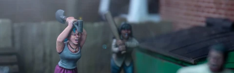 A dynamic scene features three miniature figures in a tense urban setting. In the foreground, a woman with blue hair raises a shovel, while a second figure behind her holds a baseball bat, both appearing ready to confront a threat. A third figure, dressed in a light shirt and blue pants, is seen running away, adding to the sense of urgency in the scene, with a green dumpster and a wooden fence in the background.