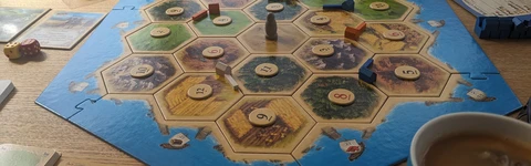 The Catan board laid out as  advised for beginners. On a dining table with tea