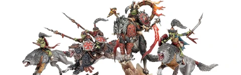 A dynamic display of goblin miniatures features several wolf-riding figures, including a prominent leader adorned with armor and a fiery banner. The miniatures are intricately detailed, showcasing vibrant colors and various weapons, set against a rocky base with tufts of grass. Additional wolf-riders and a chariot can be seen, emphasizing the theme of mobility and aggression in this new release.