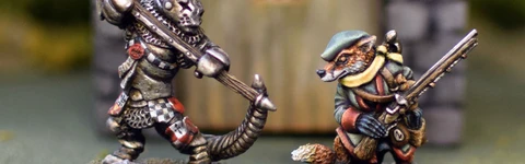 A fierce anthropomorphic badger in armor wields a large weapon, standing on the left, while a cunning-looking fox in a green hat and coat stands on the right, holding a small object. Both miniatures are detailed and painted, set against a blurred background of a stone structure with a wooden door. The scene captures the whimsical yet combative spirit of the Burrows and Badgers game.