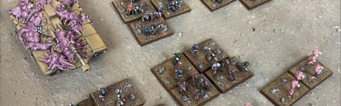 A collection of Zayken miniatures from Void Scar Miniatures is displayed on a textured surface. In the foreground, several bases feature hordes of zombified figures in various colors, including green, purple, and pink, representing the Neophyte Mobs. To the left, a tank is adorned with grotesque, bloated creatures, suggesting a fusion of machine and undead, while additional bases of zombies are scattered throughout the scene, emphasizing the overwhelming numbers of the Zayken forces.