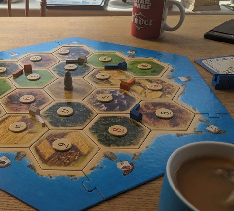 The Catan board laid out as  advised for beginners. On a dining table with tea