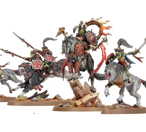 A dynamic display of goblin miniatures features several wolf-riding figures, including a prominent leader adorned with armor and a fiery banner. The miniatures are intricately detailed, showcasing vibrant colors and various weapons, set against a rocky base with tufts of grass. Additional wolf-riders and a chariot can be seen, emphasizing the theme of mobility and aggression in this new release.