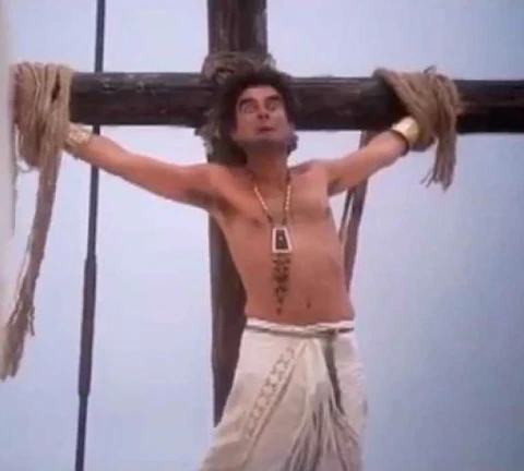 Movie still of crucifixion theme from 'The Life of Brian' where a man is bound to a cross.