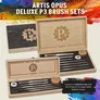A collection of Artis Opus Deluxe P3 Brush Sets displayed in a stylish wooden case featuring the P3 logo, set against a vibrant, multicolored background. The case is crafted from light wood with a black birdseye veneer, showcasing various brushes arranged neatly inside, along with a palette and a mixing guide. The text "ARTIS OPUS DELUXE P3 BRUSH SETS" is prominently featured at the top, emphasizing the quality and design of the brush sets.