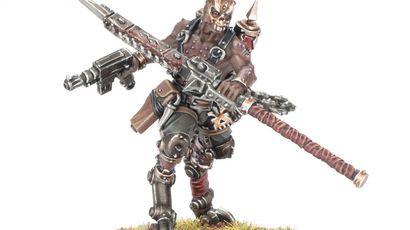 A detailed miniature figure of a Goremonger stands on a textured base adorned with tufts of grass. The figure features a muscular build, wearing a mix of armor and leather, with a menacing mask and spikes on the head. In one hand, it wields a large, jagged weapon, while a firearm is slung across its body, showcasing a gritty, post-apocalyptic aesthetic.