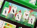 Five bird cards are displayed on a vibrant, tropical background featuring lush green foliage and colorful flowers. The cards showcase various hummingbirds: the Swallow-tailed Hummingbird, White-tipped Sicklebill, Horned Sungem, Stripe-throated Hummingbird, and Amethyst-throated Hummingbird, each with detailed illustrations and information. Below the cards, a scoring board with colored cubes indicates player progress, while a green game tray is visible in the upper right corner.