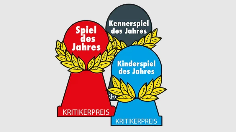 Three award trophies are displayed, each representing a different category of the Spiel des Jahres. The red trophy, labeled "Spiel des Jahres," features a laurel wreath design, symbolizing the Game of the Year. The gray trophy, labeled "Kennerspiel des Jahres," represents the Connoisseur Game of the Year, while the blue trophy, labeled "Kinderspiel des Jahres," signifies the Children's Game of the Year. All trophies are marked with the text "KRITIKERPREIS" at the base.