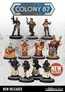 A collection of detailed tabletop miniatures is displayed, featuring a variety of characters. The top row includes a female figure with a gun, a suave male character, and a woman in a crop top, alongside three robed figures with distinct designs and colors. The bottom row showcases three soldiers in tactical gear and cloaks, all standing on textured bases, with a "NEW RELEASES" badge in the bottom right corner.